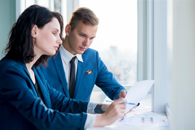 Two professional businesspeople looking at chart in office