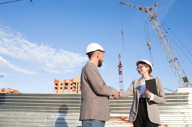 Two professional engineer shaking hand at construction site