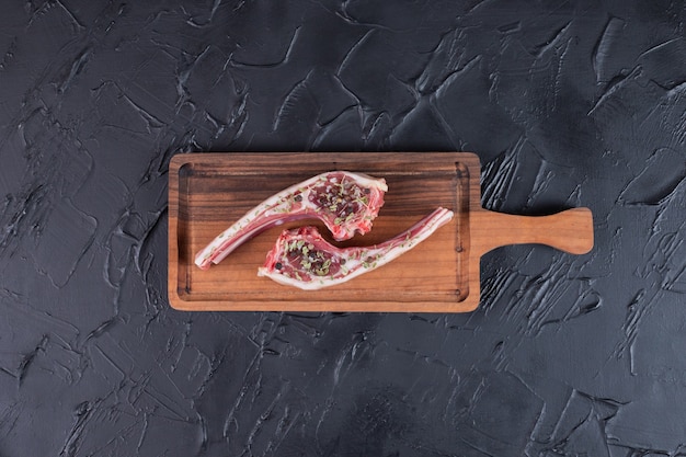 Free photo two raw beef chops on wooden board.