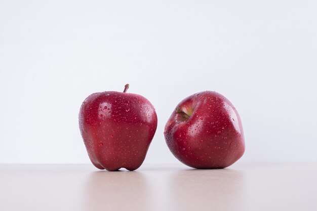 Two red apples on white.