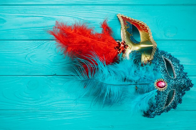 Две красные и синие венецианские карнавальные маски на синем деревянном столе