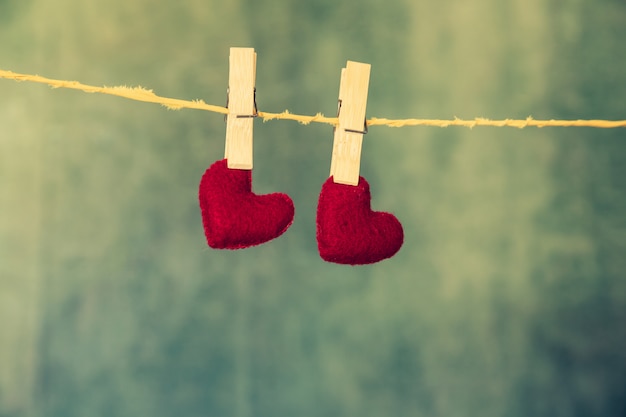 two red hearts are hanging on the rope on the blue wooden background.
