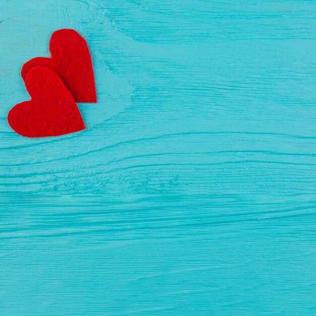 Two red hearts on blue wooden surface