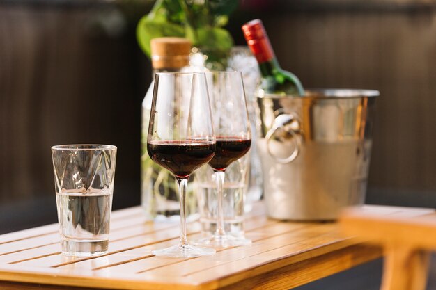 Two red wine glasses and glass of water on wooden table