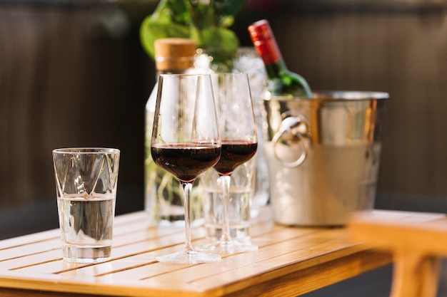 Two red wine glasses and glass of water on wooden table
