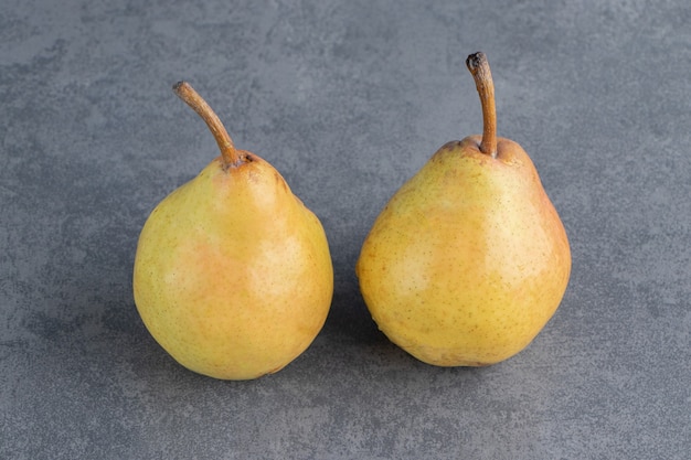 Two ripe red yellow pear fruits isolated on a gray surface