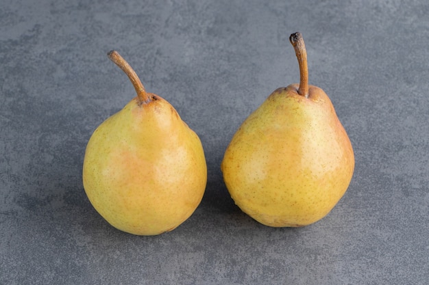 灰色の表面に分離された2つの熟した赤黄色の梨の果実