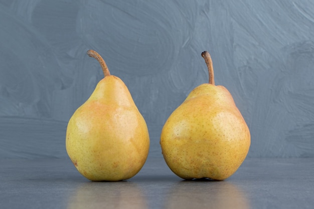 Два спелых красных желтых плода груши, изолированные на серой поверхности