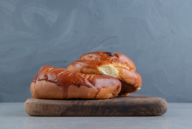 Two round pastries on wooden board.