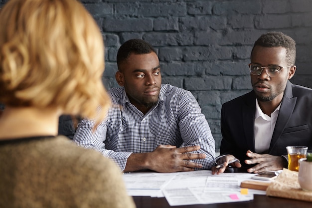 Free photo two sad dark-skinned executives having meeting with unrecognizable female