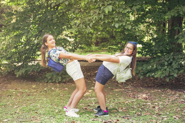 Two schoolgirls playing together in forest park