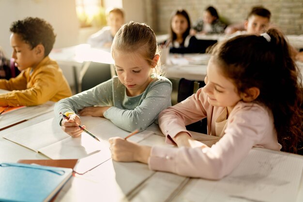 Two schoolgirls working together on a assignment in the classroom