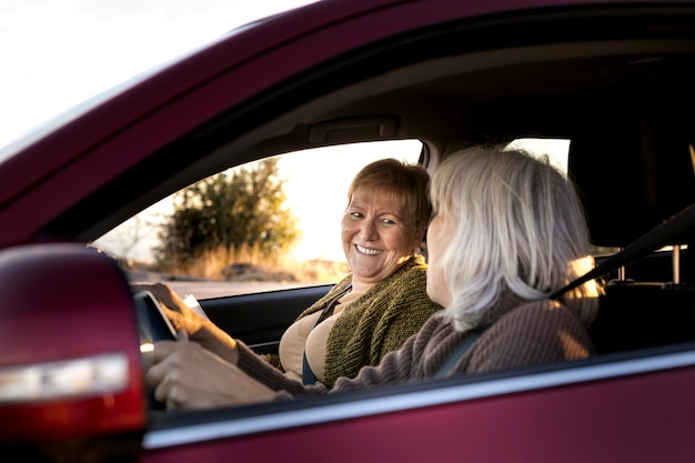 Two senior women in the car driving and going for an adventure in nature