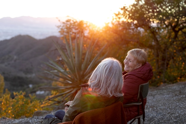 Free photo two senior women on a nature escapade sitting on chairs and enjoying their time