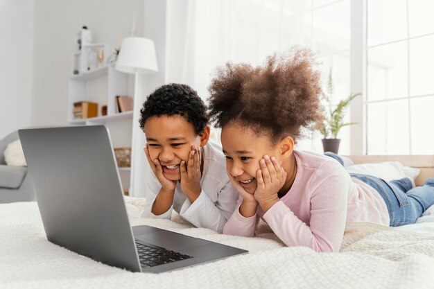 Двое братьев и сестер дома вместе играют на ноутбуке