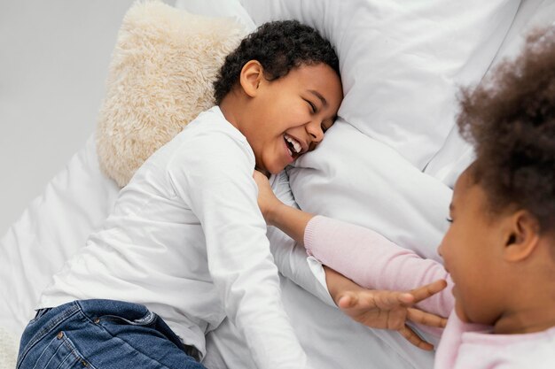 Two siblings playing in bed at home