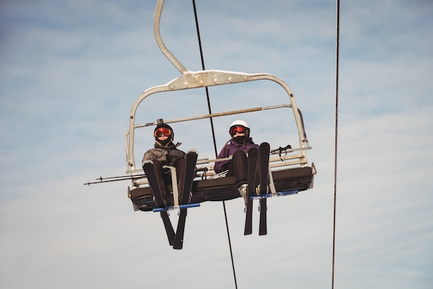 Two skiers travelling in ski lift at ski resort