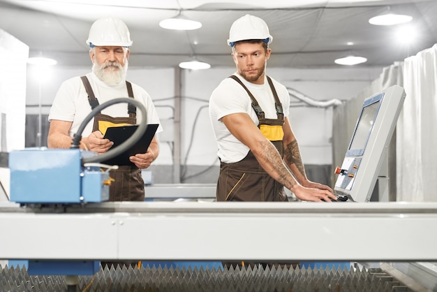 Free photo two skilled mechanics working together on metal factory