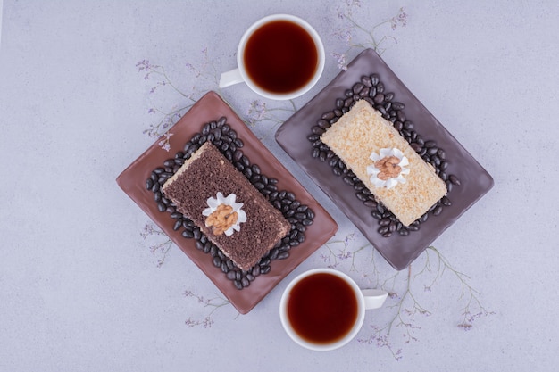 Two sliced of medovic cake with two cups of tea.