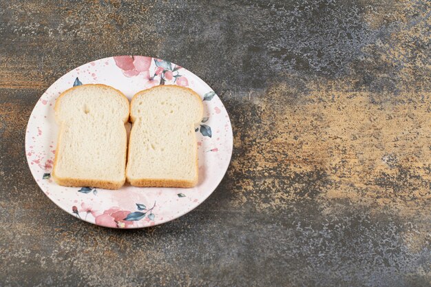 Two slices of bread on colorful plate. 