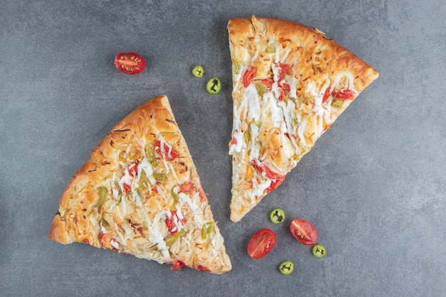 Foto gratuita due fette di pizza deliziosa con pomodorini