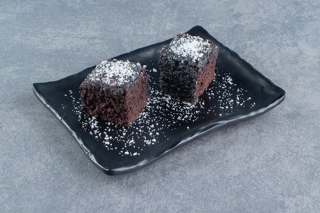 Free photo two small pieces of brownie on a dark plate