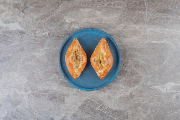 Two small servings of pide on a blue platter on marble surface