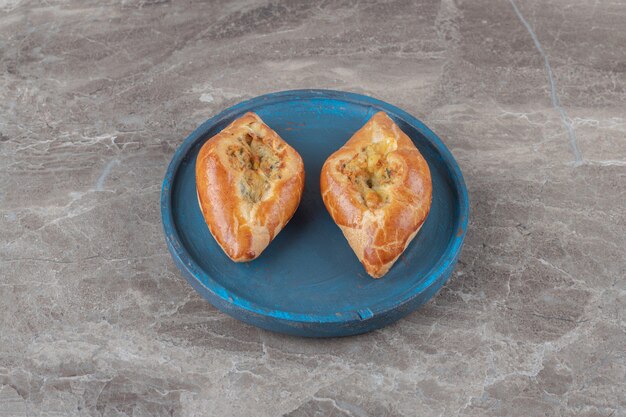 Two small servings of Turkish turkish pides on a blue platter on marble surface