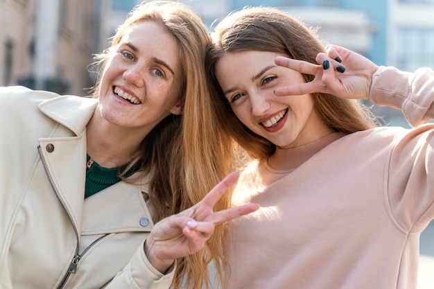 Two smiley female friends outdoors in the city posing together