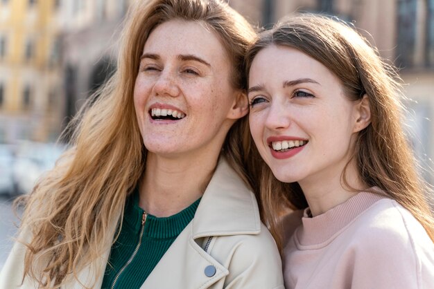 Две улыбающиеся подруги на открытом воздухе в городе