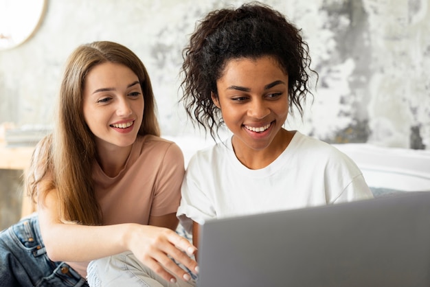 Two smiley friends looking at laptop together