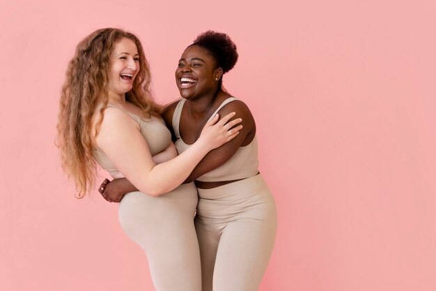Two smiley women posing while wearing a body shaper
