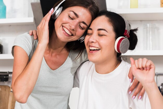 Two smiley women singing to music on headphones