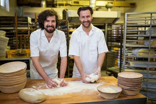 Два улыбается пекари замешивания теста