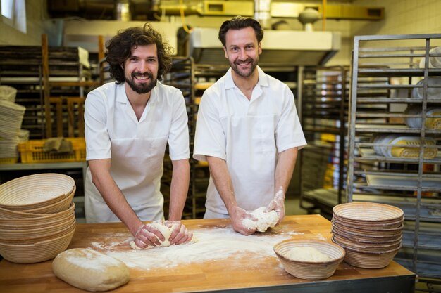 Two smiling bakers kneading dough