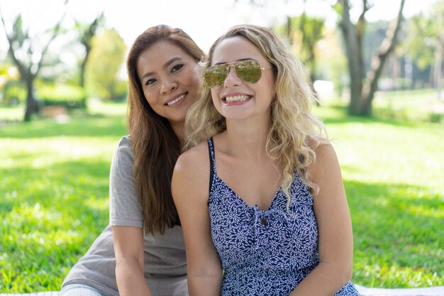 Two smiling beautiful women posing in park
