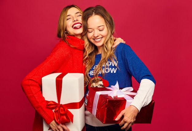 Две улыбающиеся красивые женщины в стильных свитерах с большими подарочными коробками