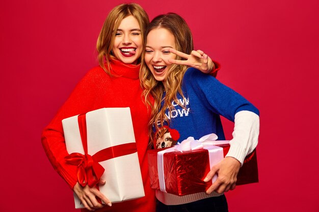 Two smiling beautiful women in stylish sweaters with big gift boxes