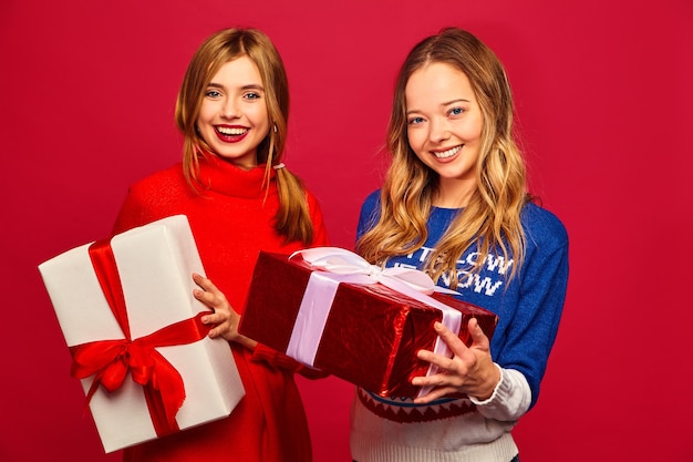 Two smiling beautiful women in stylish sweaters with big gift boxes