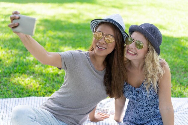 Two smiling beautiful women taking selfie photo in park