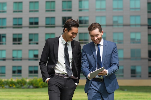 Two Smiling Business Men Using Tablet and Walking