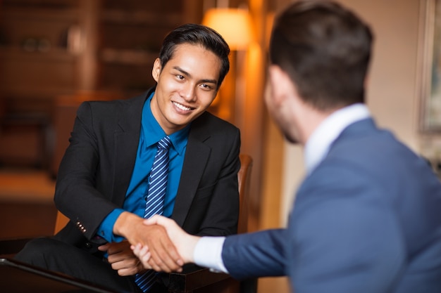 Free photo two smiling business partners shaking hands