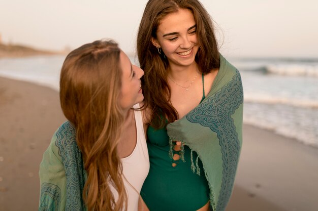 Две улыбающиеся подружки, наслаждаясь на пляже