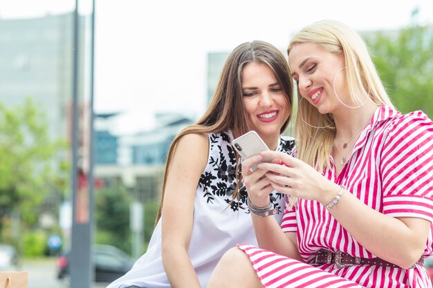 Two smiling female friends looking at mobile phone