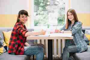 Free photo two smiling girls at desk with textbooks