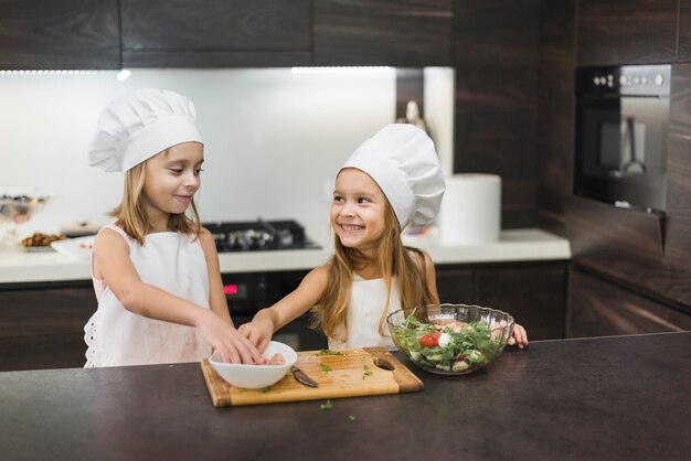 Two smiling girls preparing food in kitchen