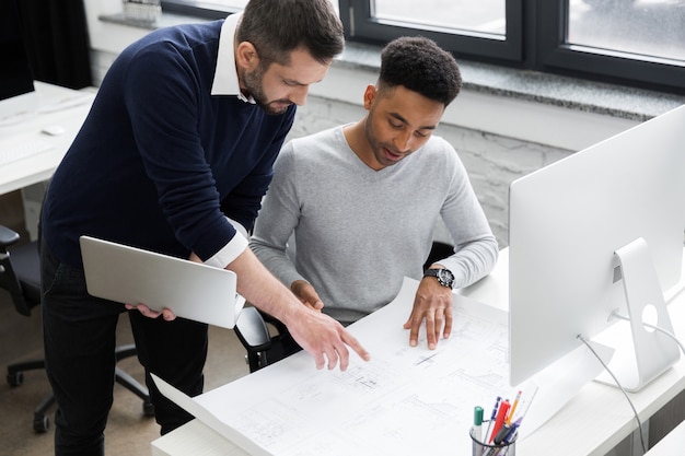 Two smiling male office workers working with laptop