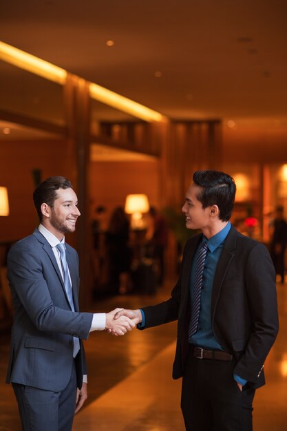 Two Smiling Partners Shaking Hands in Lounge