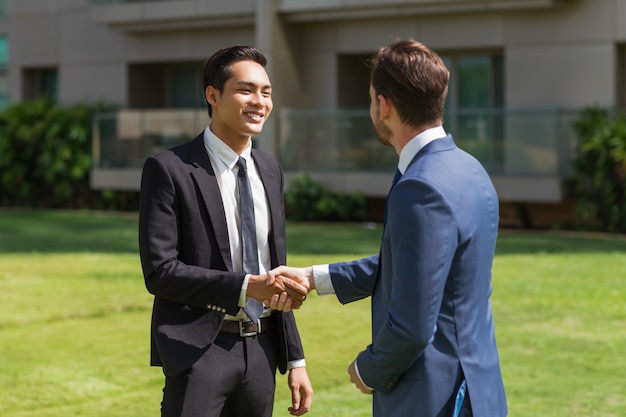 Two Smiling Partners Shaking Hands Outdoors