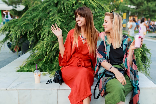 Two smiling woman talking and spending time  together in sunny modern city